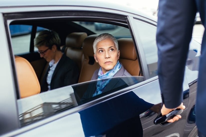 senior-business-woman-her-assistant-sitting-limousine-talking-working_473712-1182