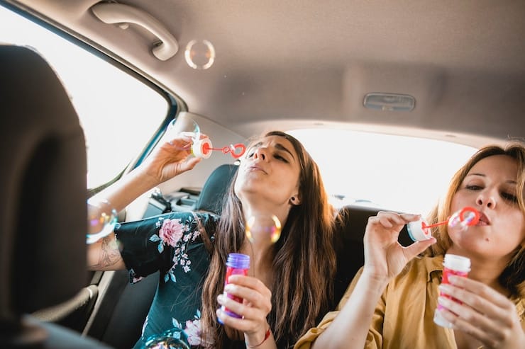 women-blowing-bubbles-car_23-2147829743