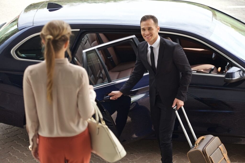 Professional chauffeur assisting passenger with luggage in Boston.