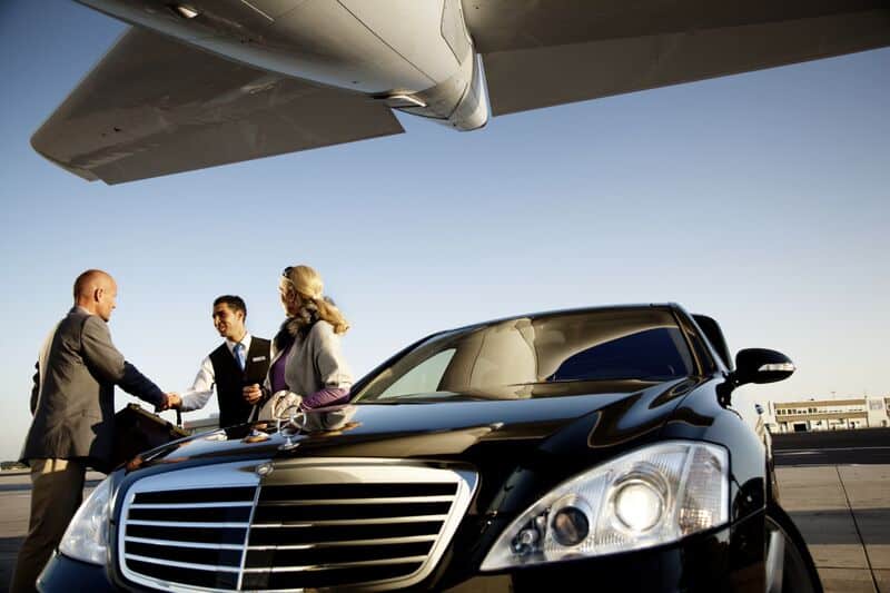 Chauffeur greeting clients under airplane wing at Logan Airport Boston for late-night flights.