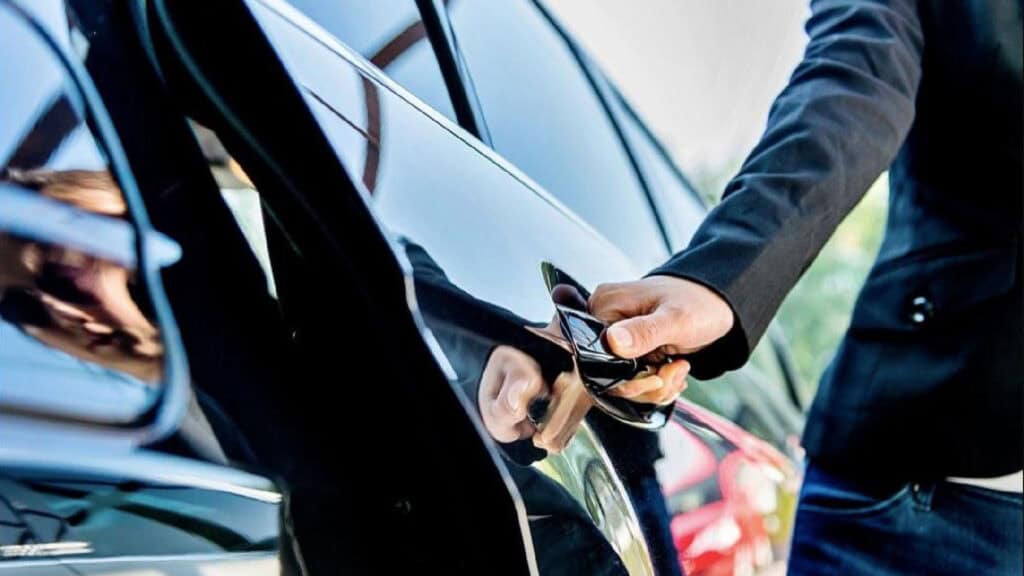 Professional chauffeur opening car door for long-distance Boston travel service.