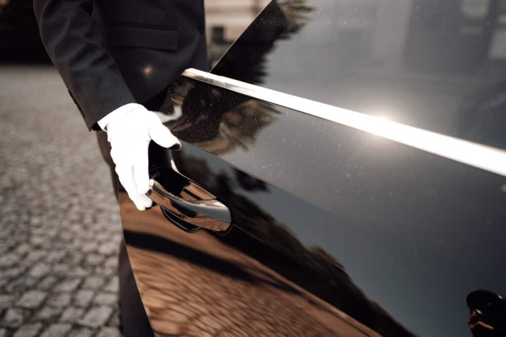 Chauffeur opening car door for a luxury ride, professional service.