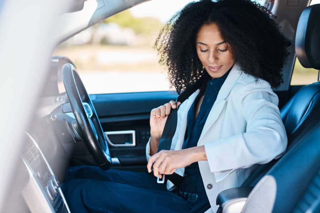 Woman in business attire securing seatbelt in luxury car for chauffeur service.