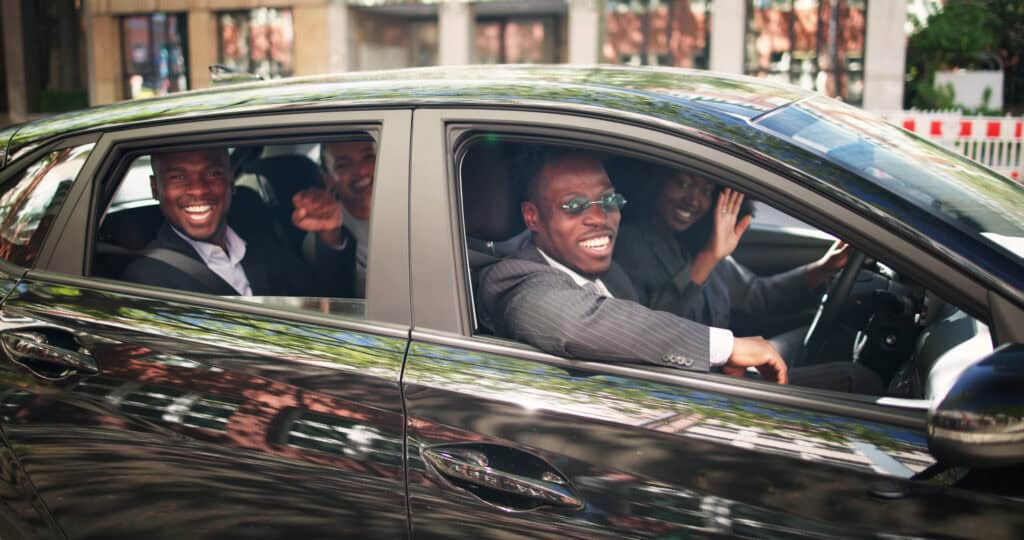 Group of happy passengers enjoying luxury chauffeur service in a black car.