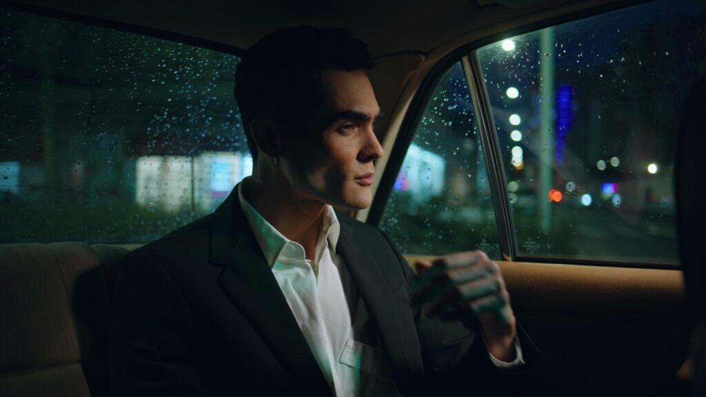 An elegant man in a suit sitting in a luxury car during nighttime, providing professional chauffeur.