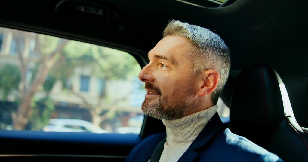Man enjoying luxury chauffeur service in a modern vehicle.