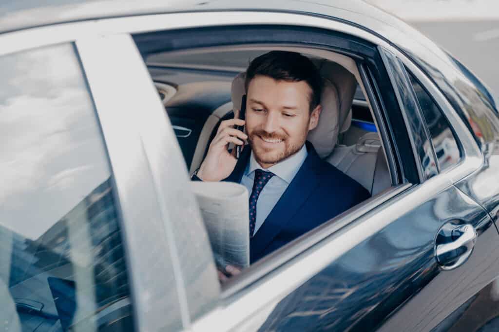 Professional chauffeur speaking on phone inside luxury car for premium transportation.