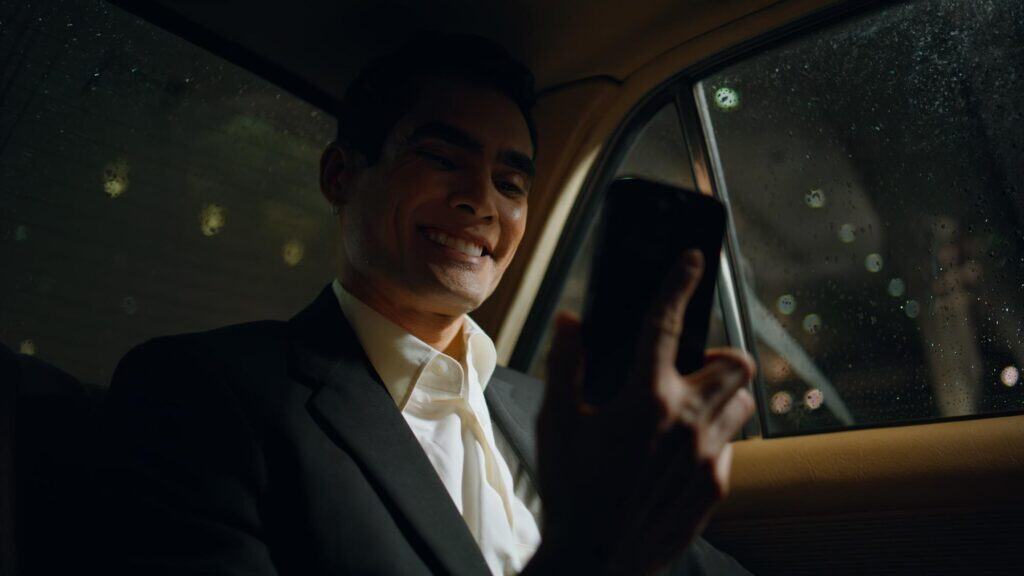 Luxury chauffeur service with a smiling driver using a smartphone inside a private car.