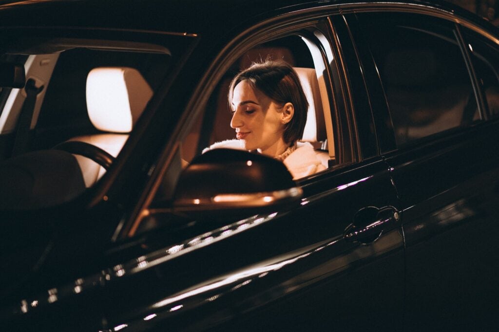Woman enjoying a luxury chauffeur-driven car ride at night.