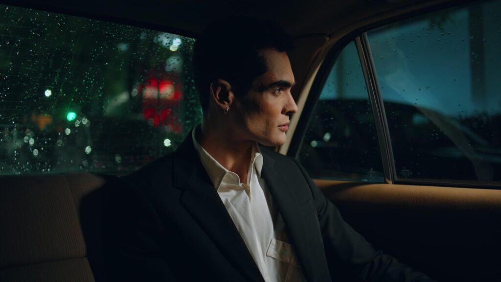 Man in formal suit sitting in luxury car at night, chauffeur service.